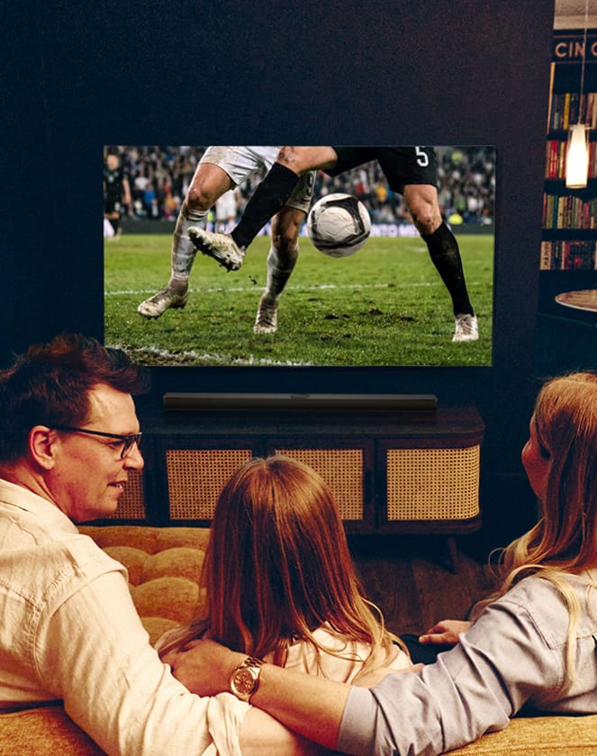 Famiglia che guarda una partita di calcio in TV vista da dietro