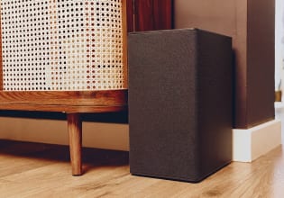 Subwoofer wireless posizionato accanto a un mobile in legno in un soggiorno