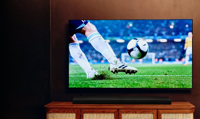 Grande TV che mostra una partita di calcio sopra un mobile TV in legno in un accogliente soggiorno.
