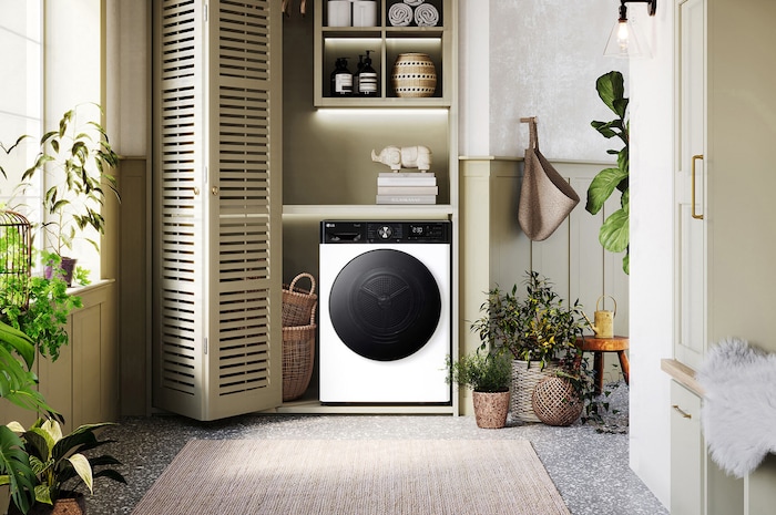 Asciugatrice LG RH90V9LVEN Bianca, elegantemente integrata in un vano lavanderia verde chiaro con mensole in legno e piante.