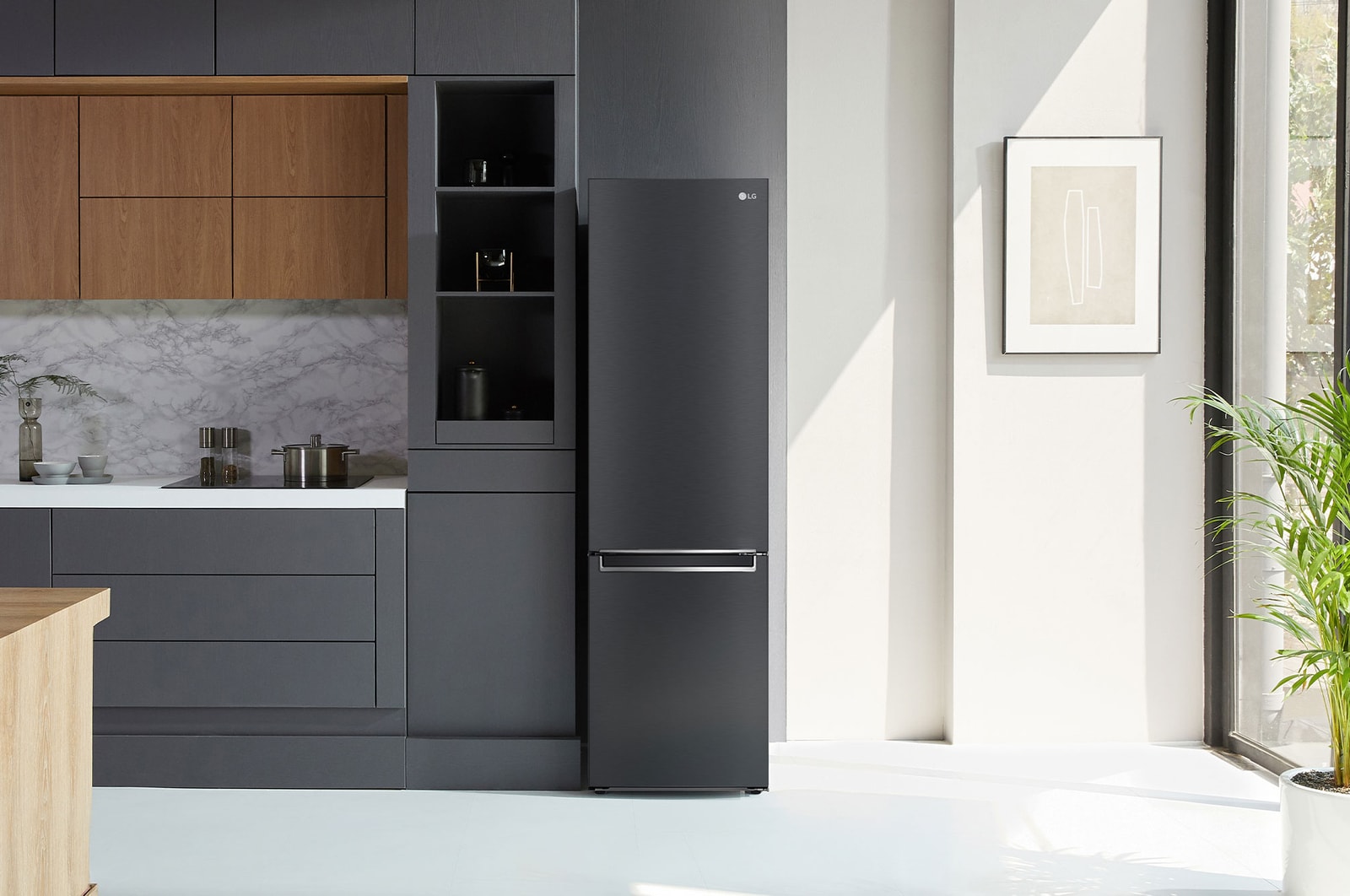 Frigorifero Combinato LG GBB72MCVBN Matte Black, integrato in una moderna cucina dai toni verdi con pavimento in legno e piante.