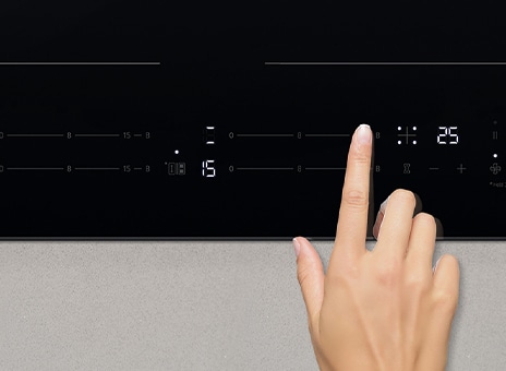 Immagine di un dito che tocca il pannello di controllo del piano a induzione.