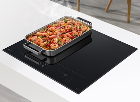 Piano cottura a induzione LG con padella di gamberi e verdure che emette vapore, su un piano cucina bianco.