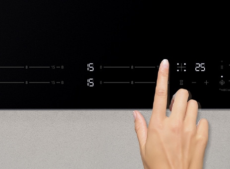 Immagine di un dito che tocca il pannello di controllo del piano a induzione.