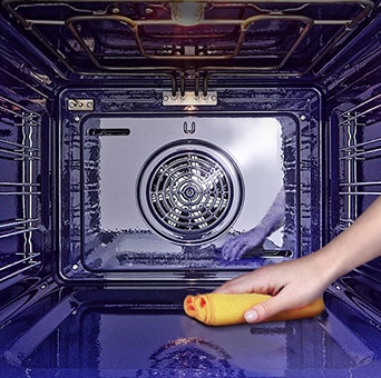   Immagine di una mano che pulisce il forno con una spugna.