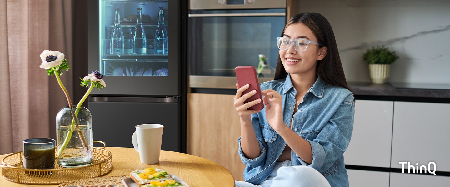 L'immagine di una donna che tocca il suo telefono in cucina, sullo sfondo un frigorifero MoodUP