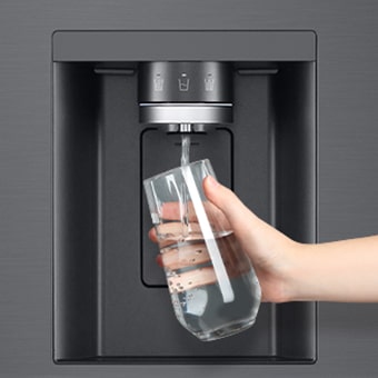 Foto di una mano che tiene un bicchiere mentre lo riempie di acqua sotto al dispenser del frigo.
