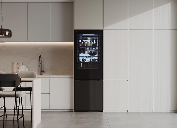 Congelatore inferiore LG InstaView (GBGW92GCEV) integrato in mobili alti color crema accanto a un'isola di marmo con sgabelli da bar	