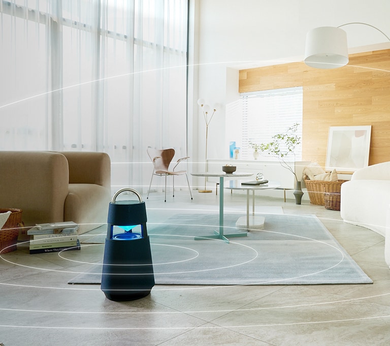 Immagine delle onde sonore che si diffondono intorno all’XBOOM 360 collocato sul pavimento di un salotto dallo stile minimal.