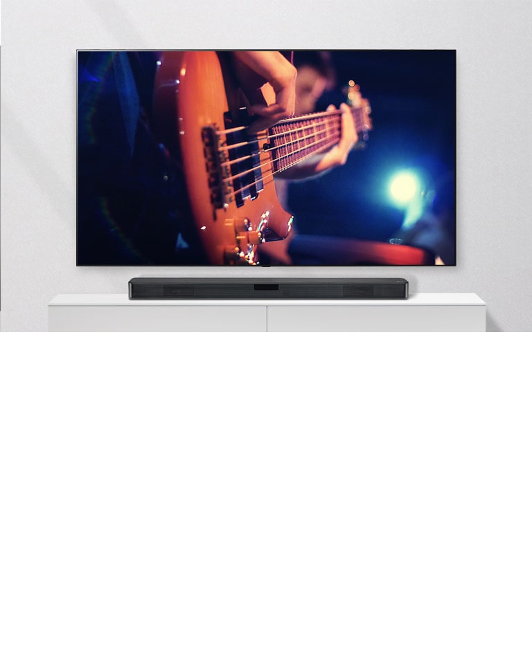 Il televisore è appeso alla parete, la soundbar è posizionata su un ripiano bianco.