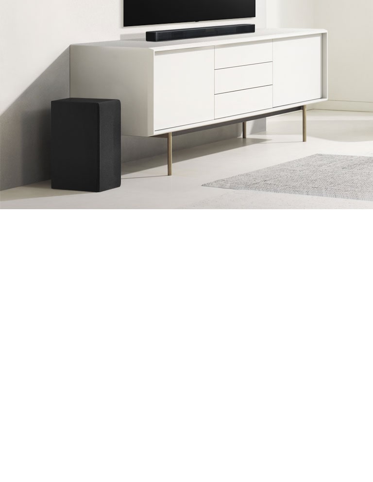 La soundbar è posizionata sul mobile bianco, alla cui sinistra si trova il subwoofer.