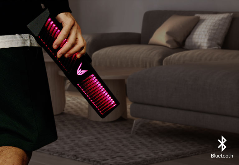 Un uomo tiene in mano l’altoparlante da gaming dotato di illuminazione di colore rosa. Sullo sfondo si vede un salotto.