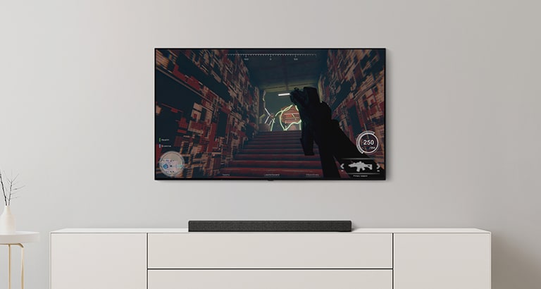 In un salotto bianco ci sono un TV e una Soundbar. Sullo schermo di un TV vediamo un gioco FPS e il canale TV viene cambiato per passare a una partita di calcio. (riprodurre il video)