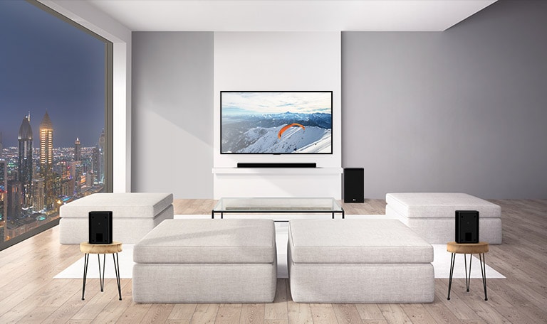 Soundbar LG con sub-woofer e 2 altoparlanti che emettono audio verso l’alto in un salotto. Grafica delle onde audio che fuoriescono dagli altoparlanti posteriori fino al soffitto e poi rimbalzano indietro. (riprodurre il video)