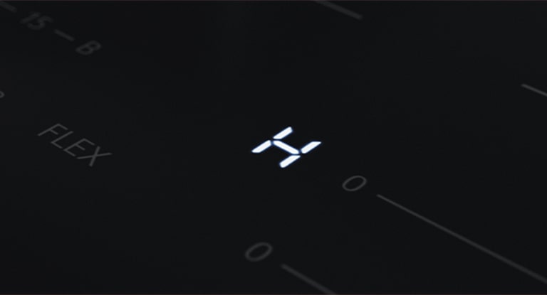 Gros plan du voyant LED "H", un indicateur de chaleur résiduelle sur la plaque à induction.