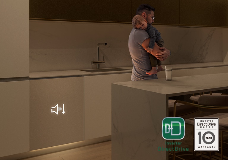 Un uomo con in braccio un bambino che dorme in una cucina con luce soffusa. Nel frattempo, la lavastoviglie sta funzionando in maniera silenziosa.