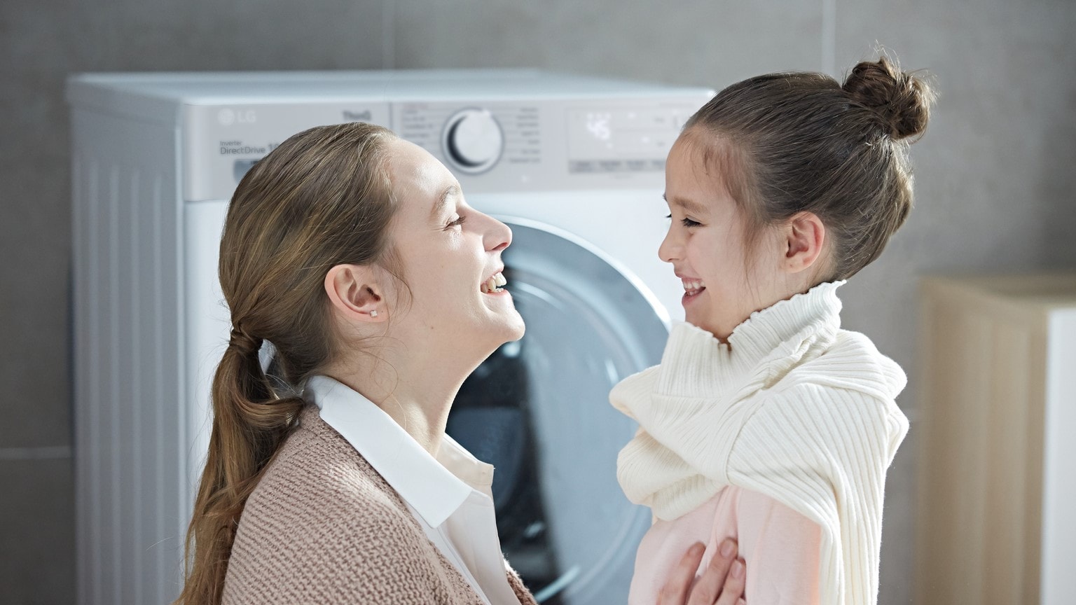 Moda sostenibile: mamma e bambina che lavano i vestiti vicino alla lavatrice LG