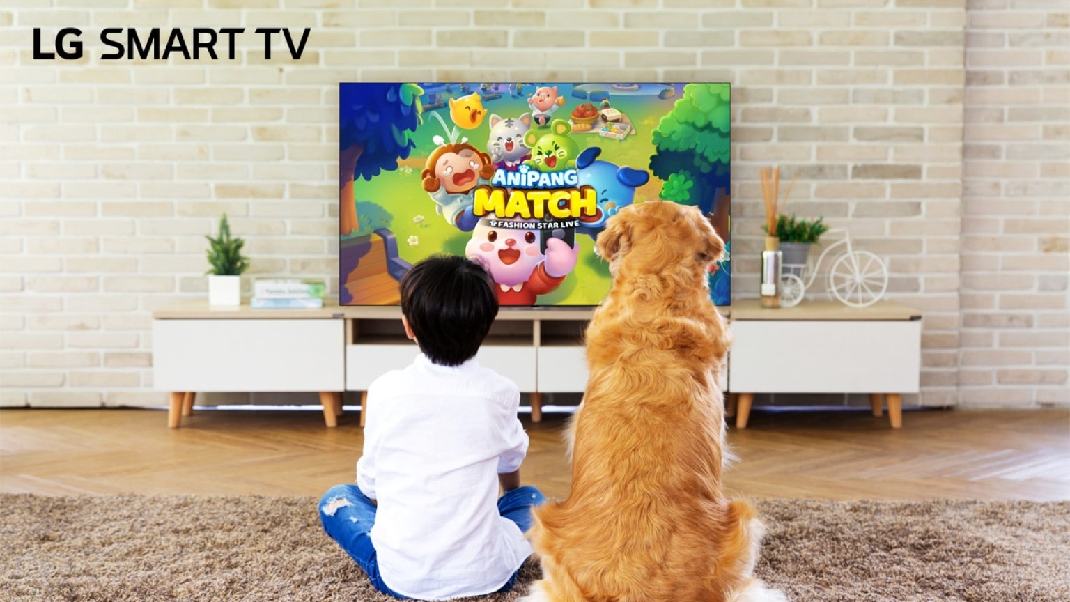Cartoni educativi per bambini: immagine di un bambino e un cane che guardano i cartoni animati seduti su un tappeto di spalle di fronte a un TV QNED LG. 