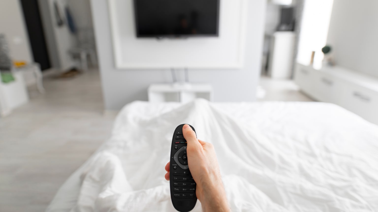 Tv in camera: immagine di televisore e persona a letto con telecomando