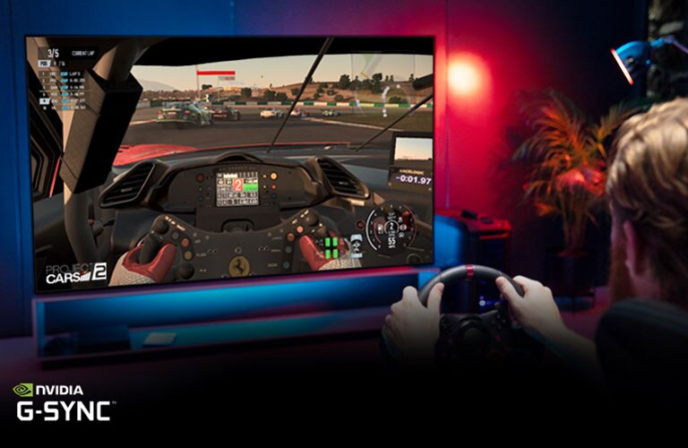 Un uomo seduto su una sedia da gaming con in mano un volante gareggia in un gioco da corsa sullo schermo del TV