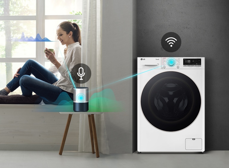 Lavatrice LG connessa tramite Wi-Fi a un dispositivo vocale su un tavolo, vicino a una persona seduta su un davanzale.