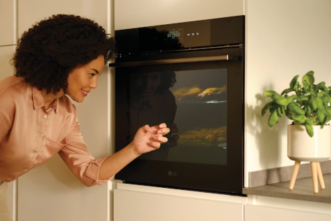 Immagine di una donna che bussa sul forno InstaView per accendere la luce e guardare al suo interno.