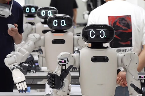 A line of LG humanoid service robots with digital faces, standing in a room.