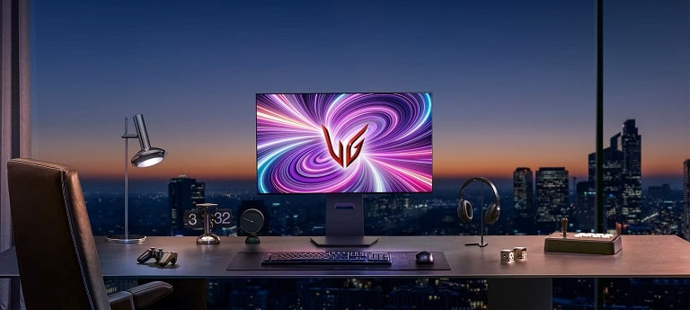 Una postazione gaming elegante con un monitor LG UltraGear illuminato da luci colorate, affacciata su un panorama urbano al tramonto attraverso una grande finestra.