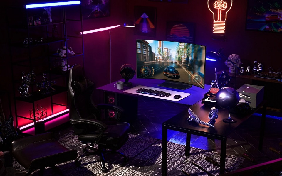 Una sala da gaming con un monitor curvo che mostra un gioco di corse, decorata con luci al neon, accessori da gaming e una sedia da gaming.