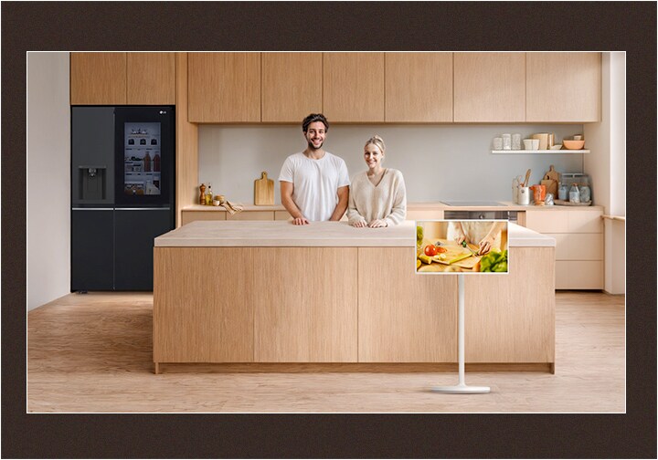 Immagine di una cucina ordinata e di una coppia che guarda dritto con sorrisi felici.