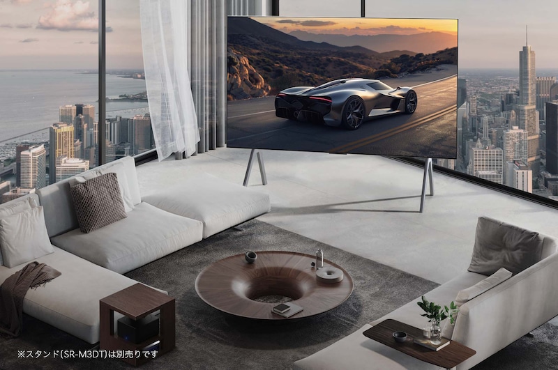 Spacious living room with a view of a cityscape. LG OLED TV is on a stand. The Ultra Slim Design makes the screen feel immersive.  Zero Connect Box is visible, but concealed. 