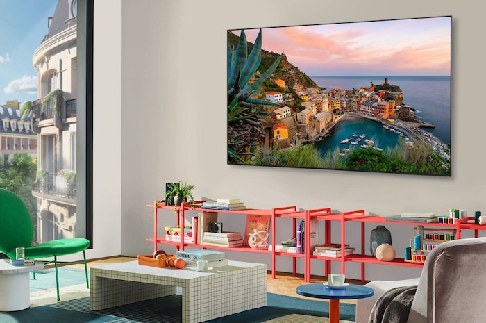 スタイリッシュでカラフルなリビングルームのパノラマ画像。LG OLED evo AI C5 4KスマートTVが壁に設置され、その下にLG Soundbarがある。TVのデザインが空間になじんでいる。TV画面にはカラフルなアートワークが表示されている。