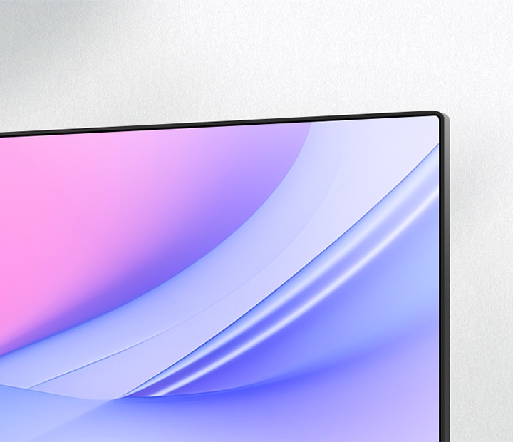 モニター右上コーナーを斜めから捉えたクローズアップで、極細ベゼルと一体感のある画面デザインを際立たせています。ディスプレイにはピンクからブルーへと滑らかに変化するグラデーションが映し出され、ミニマルな空間に調和する、クリーンでモダンな美しさを演出します。
