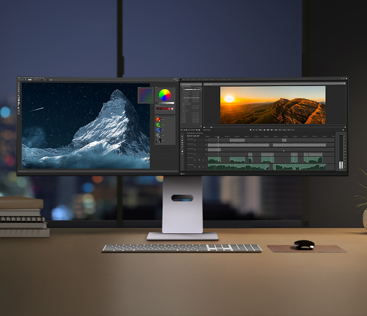 LG UltraWide™ Monitorを使用した夜のクリエイティブな作業空間。広い画面には写真編集ソフトと動画編集ソフトが表示され、周囲にはデスクアクセサリーとやわらかな間接照明が配置されています。