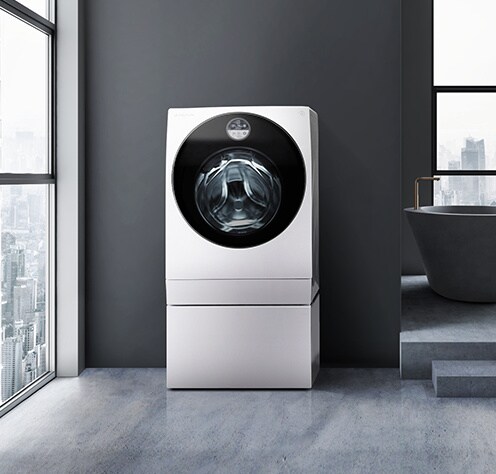 LG SIGNATURE WashingMachineは、暗いランドリールームで自分自身を見渡すシティビューを表示するウィンドウの隣に表示されます。