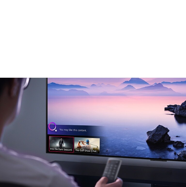 Closeup of a man choosing what to watch on TV with a remote control, with TV showing landscape.