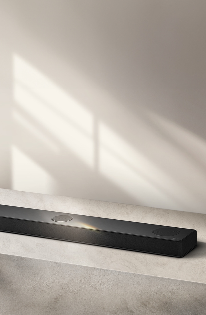 LG Soundbar на cерой поверхности на сером фоне в угловой воздушной перспективе.