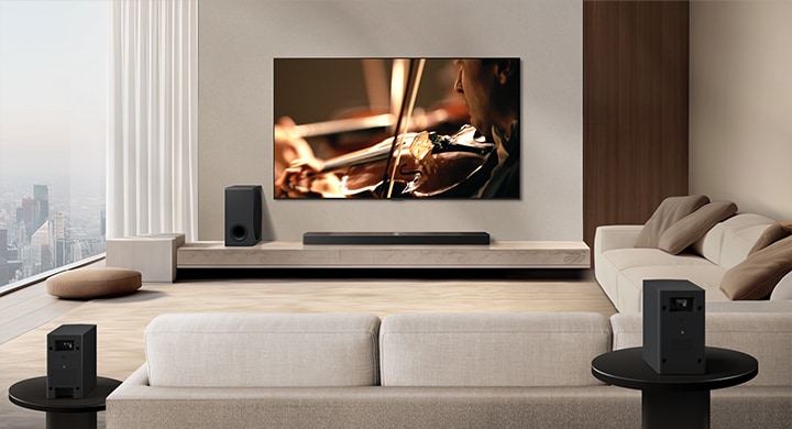 Саундбар LG Soundbar, телевизор LG TV, сабвуфер и задние динамики находятся в современной городской квартире. Фон затемняется, и поверх изображения с телевизора LG TV появляется наложение в виде сетки, как при сканировании пространства. Пунктирная линия идет от одного из задних динамиков, чтобы показать, что два задних динамика расположены линейно. Белые звуковые шарики собираются вместе и образуют волны, наполняя комнату звуком.