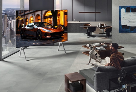 Гостиная с LG True Wireless TV на подставке. Zero Connect Box едва заметен под боковым столиком рядом с диваном, что показывает, как легко его можно разместить в любом месте. Вся планировка гостиной выглядит аккуратно и опрятно. 