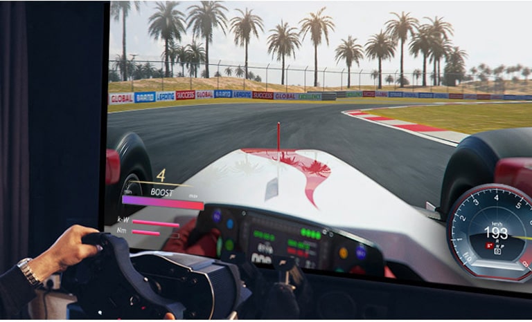 Крупный план игрока, держащего в руках руль и играющего на телевизоре в гонки.