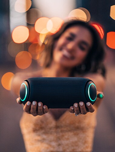 Top-down view of the LG XBOOM Go PL7 on a wooden surface surrounded by slippers, sunglasses and a straw hat