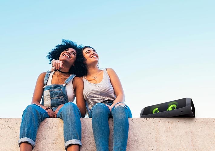 Then the other picture comes up, two women sitting and listening to Xboom outdoor in an open area.