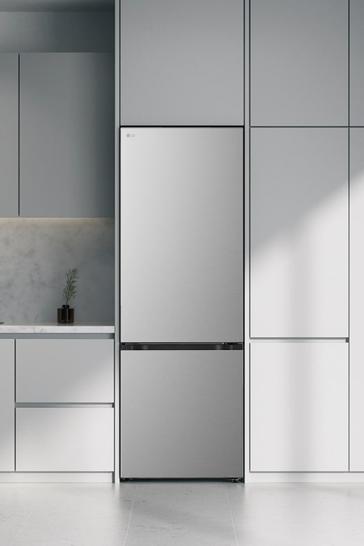 Серебристый холодильник LG с нижней морозильной камерой (GC-B640FMBM) рядом с мраморной столешницей, индукционной плитой и большим окном справа