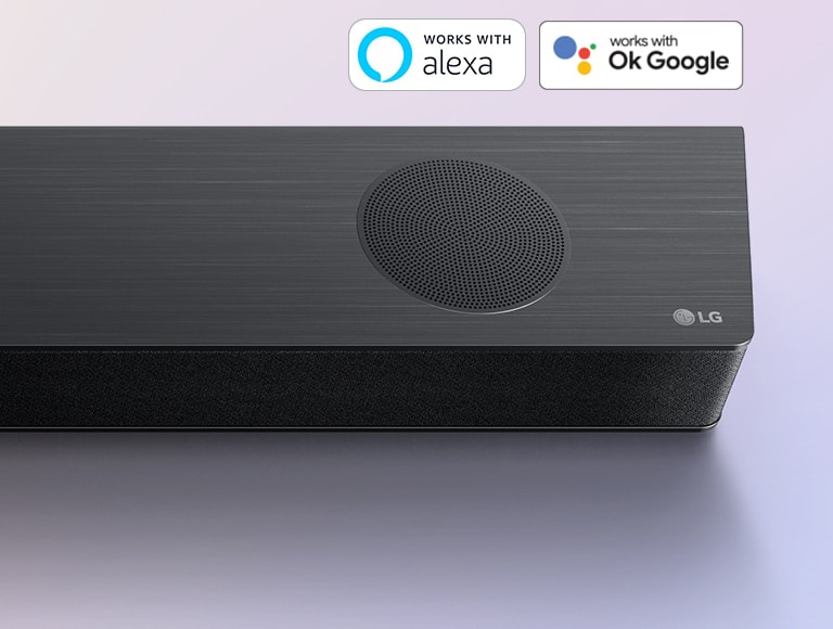 Саундбар LG расположен на земле, с логотипом LG в правом углу. Логотип Alexa и логотипы OK GOOGLE размещены на саундбаре.
