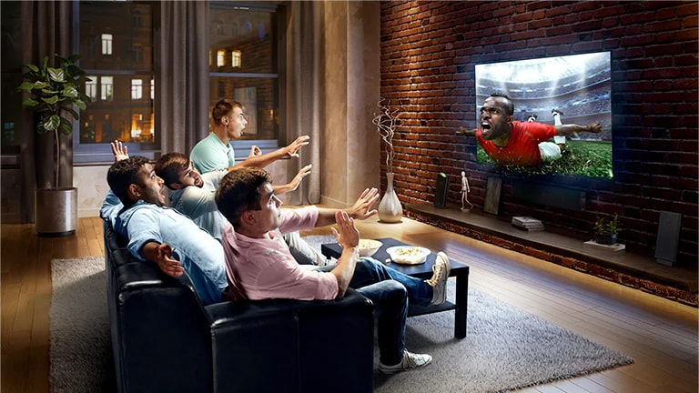 Бұл карточкада Virtual Surround Plus технологиясы көрсетілген. Отбасы диванда теледидар экранынан футбол көріп отыр.