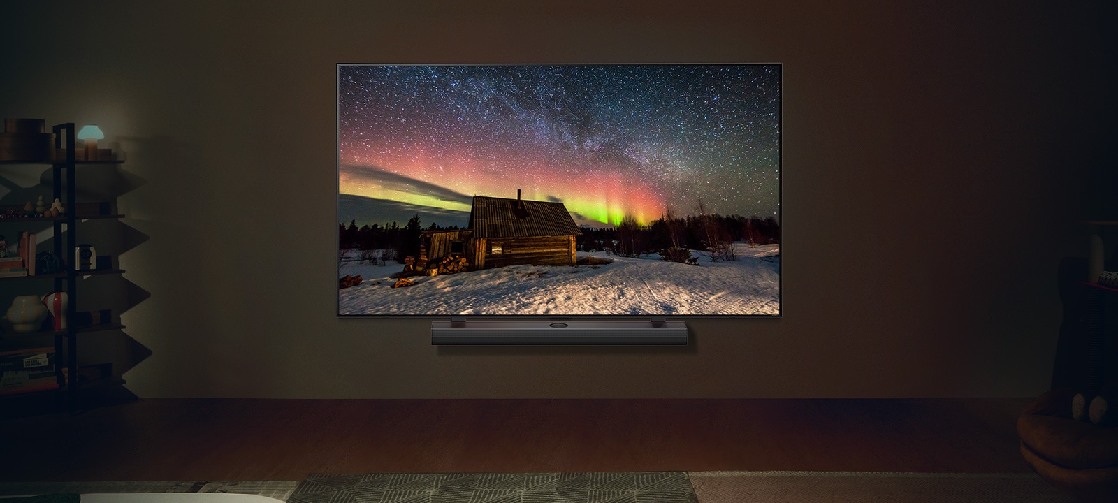 La LG TV et la LG Soundbar dans un espace de vie moderne de nuit. L’image à l’écran d’une aurore boréale est affichée, avec des niveaux de luminosité parfaits.	