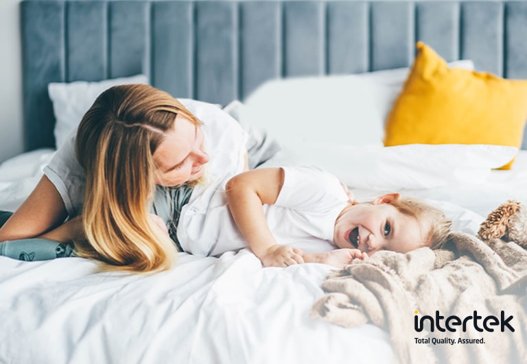 Une femme et un enfant sont allongés dans un lit en souriant.