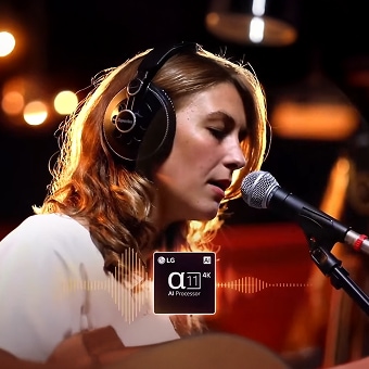 Une femme chante dans un micro avec un casque audio, mise en valeur par l’amélioration sonore du processeur LG α11 AI.