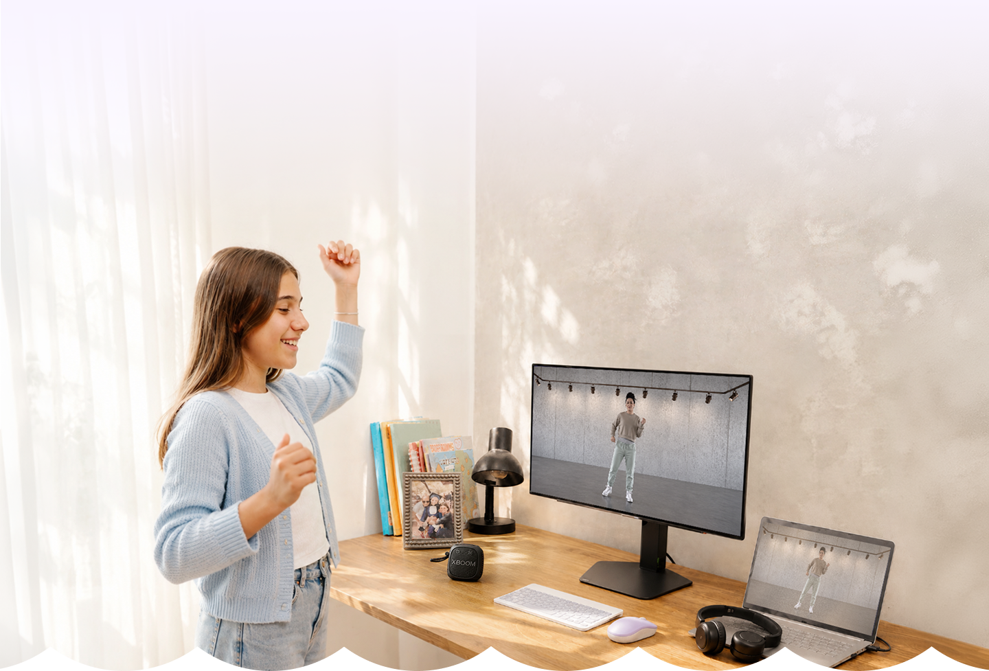 Adolescente bailando un juego de ritmo en el monitor LG, con la bocina xboom y una laptop en el escritorio