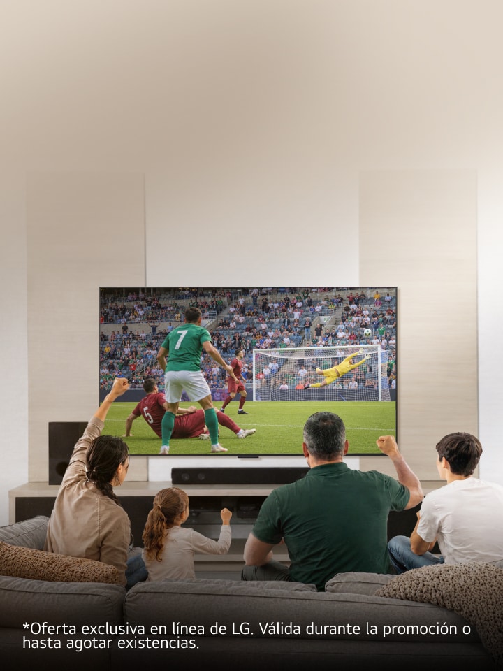 Una familia sentada en el sofá de la sala disfruta y celebra un partido de fútbol en una pantalla grande.